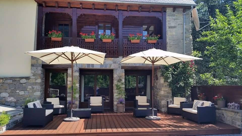 Sun terrace in summer with parasols, geraniums on the carved wooden balcony